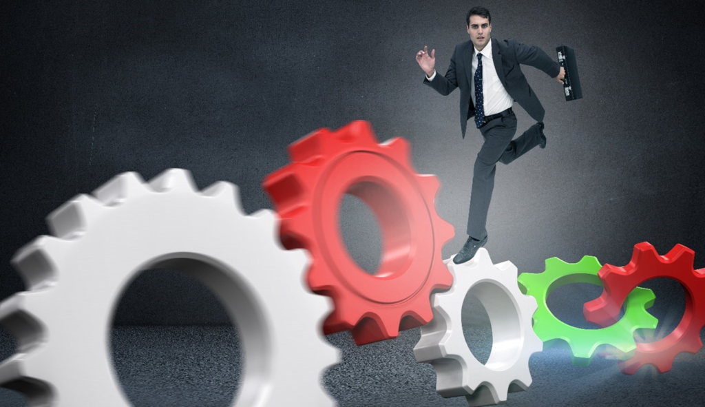 Businessman in a suit, holding a briefcase, running across a series of interconnected, oversized gears.